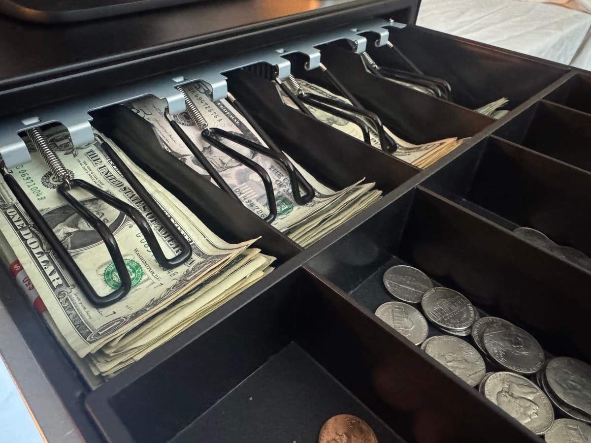 An open BlazeBite cash drawer with bills and coins