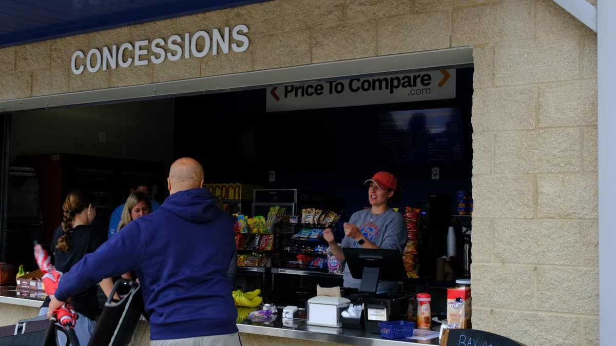 A school concession window on a game day, with a worker serving customers at the counter