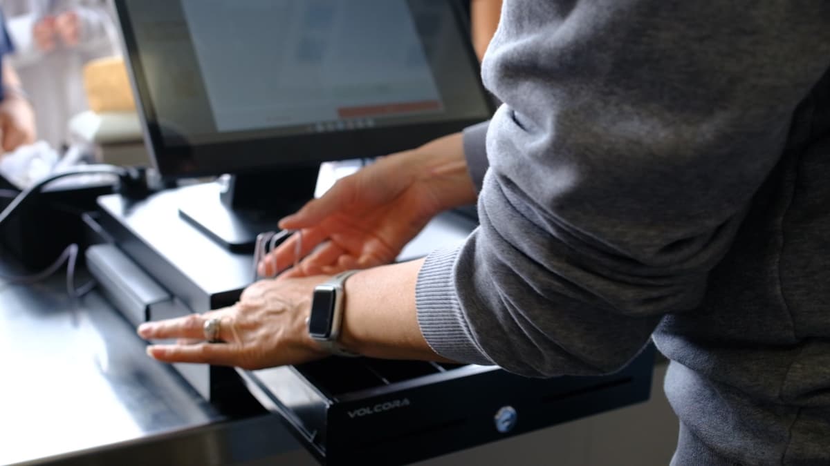 A hand tapping a card on the reader beside a BlazeBite terminal