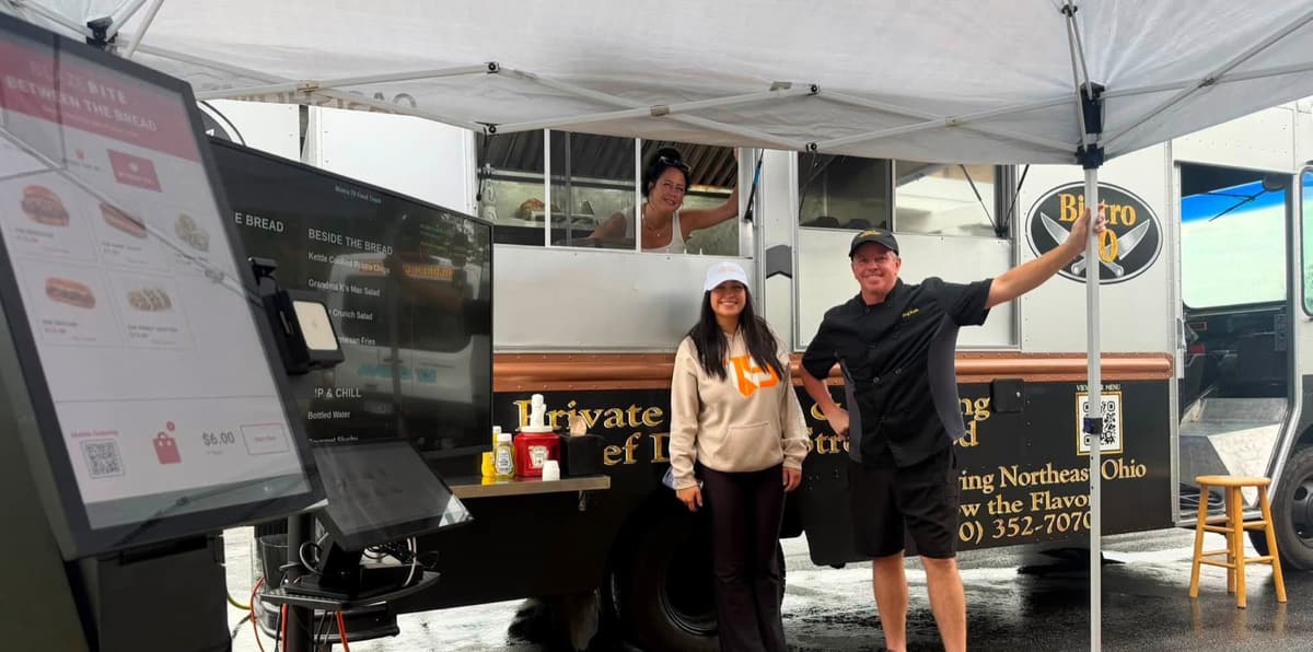 The Bistro 70 food truck set up at an event, with the team under the tent beside it