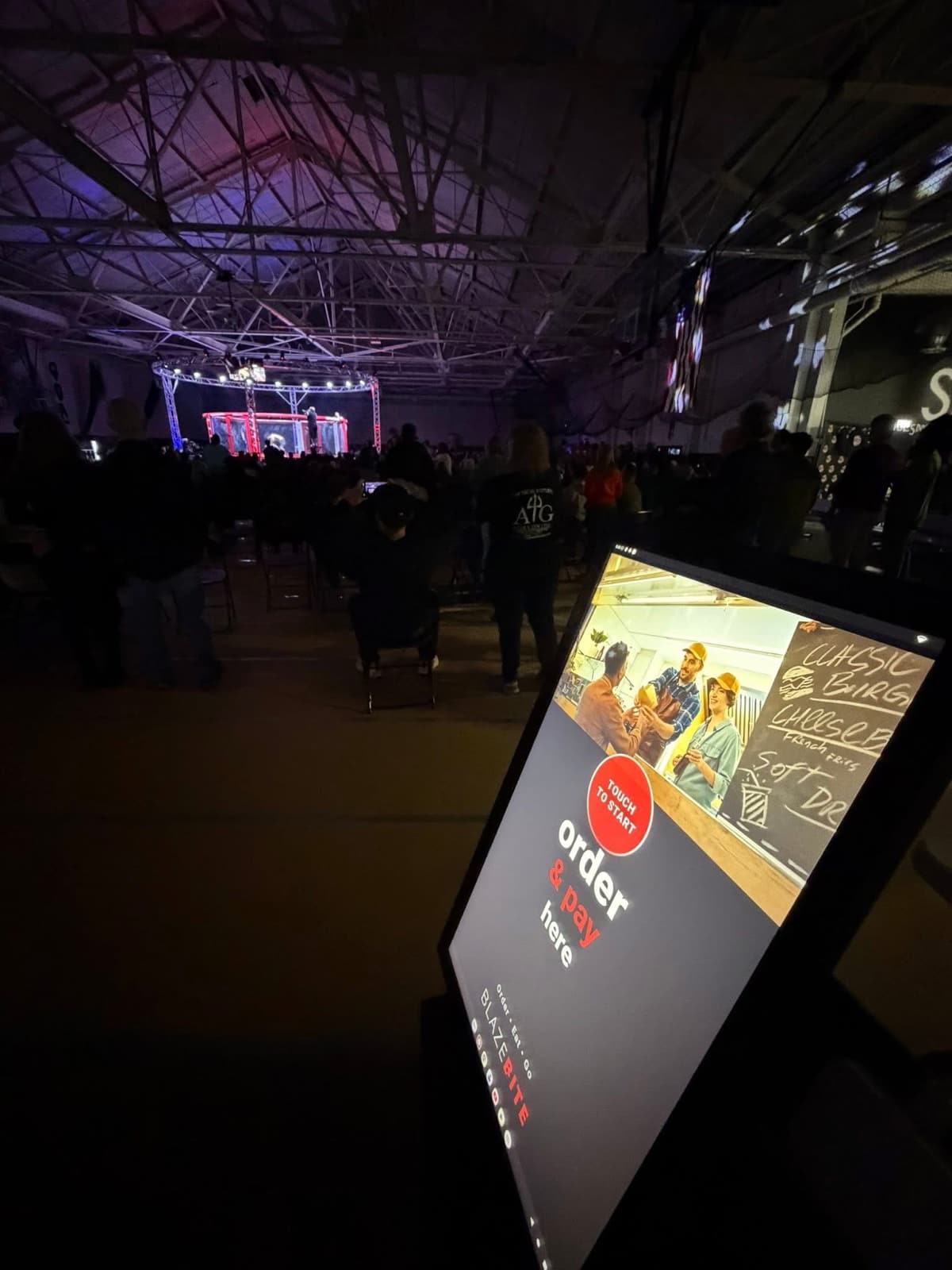 A BlazeBite kiosk lit up at an indoor event, with the order and pay screen showing