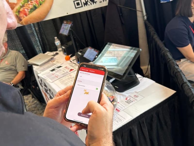 A customer holding a phone with the BlazeBite menu open at a table