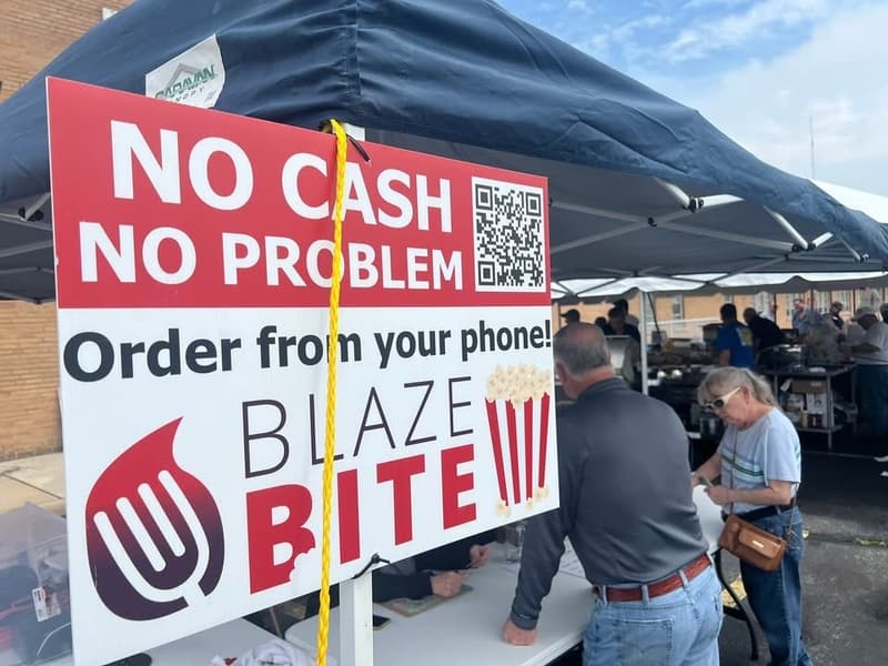 A No Cash No Problem BlazeBite sign at a tent at an outdoor event